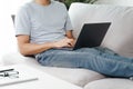 Young man sitting on the sofa at home typing on the laptop keyboard for online working, using internet, freelancer, relaxed,