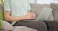 Young man sitting on sofa with laptop and papers with bills calculating