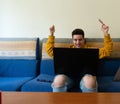 Young man sitting on a sofa, online shopping in his laptop, with a credit card on his hand Royalty Free Stock Photo