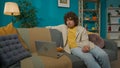 Young man sitting on the sofa in the room, eating snacks and watching a movie on laptop Royalty Free Stock Photo