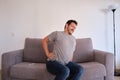 Young man sitting on a sofa suffering from low back pain Royalty Free Stock Photo