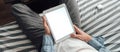 Young man sitting on a sofa uses a tablet computer with white screen. mock up Royalty Free Stock Photo