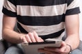 young man sitting on sofa while using his digital tablet and reading news Royalty Free Stock Photo