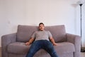 Young man sitting on a sofa watching television absorbed with his mouth opened