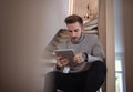 Young man sitting on stairs indoors in office, using tablet. Royalty Free Stock Photo