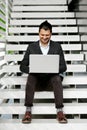 Young man sitting on the stairs using laptop.