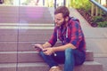 Young man sitting on stairs and using tablet PC Royalty Free Stock Photo