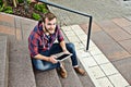 Young man sitting on stairs and using tablet PC Royalty Free Stock Photo
