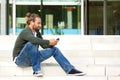 Young man sitting on steps listening to music with cell phone Royalty Free Stock Photo