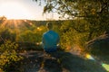 Young man sitting on stone and looking to Czech ore mountain valley at sunset landscape