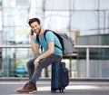 Young man sitting on suitcase and calling by cellphone Royalty Free Stock Photo