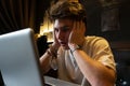 Young man sits at a table in front of a laptop. Royalty Free Stock Photo