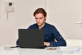 young man sitting on a table using a laptop next to some bills Royalty Free Stock Photo