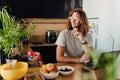 Young man sitting by table while working on laptop in office kitchen Royalty Free Stock Photo