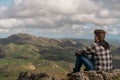 Young man sitting at the top of the mountain and looking at the horizon Royalty Free Stock Photo