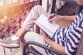 Young man sitting on Vintage chair holding pen writing on paper and reading book Royalty Free Stock Photo