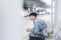 Young man is sitting and waiting for bus. He is holding backpack and listening to music from earphones. Guy is looking forward Royalty Free Stock Photo