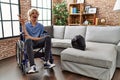 Young man sitting on wheelchair at for motorcycle accident smiling with happy face winking at the camera doing victory sign Royalty Free Stock Photo