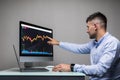 Young man sitting on work market view of the computer screens of a stock broker trading in a bull market showing ascending graphs Royalty Free Stock Photo