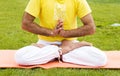 Young man sitting in yoga pose at green grass in the meadow and meditates. Muscular guy relaxing in lotus pose. Royalty Free Stock Photo