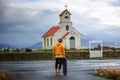 Young man with a skateboard looking at a church with a cemetery in Iceland Royalty Free Stock Photo