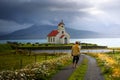 Young man with a skateboard looking at a church with a cemetery in Iceland Royalty Free Stock Photo