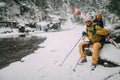 Young man with ski sitting in the snow forest