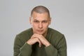 A young man is skinhead in a green military style sweater. studio. Royalty Free Stock Photo