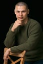 A young man is skinhead in a green military style sweater. studio.