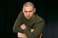 A young man is skinhead in a green military style sweater. studio. Royalty Free Stock Photo