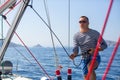 Young man skipper at his sail boat, controls ship during sea yacht race. Royalty Free Stock Photo