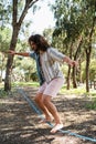 Young man slacklining in the city park during summer day
