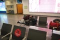 Young man is sleeping at airport while waiting for delay flight. Airport lounge and people waiting for boarding. Male sleeping on Royalty Free Stock Photo