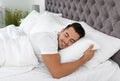 Young man sleeping in bed with soft pillows