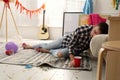 Young man sleeping near sofa in room after party Royalty Free Stock Photo