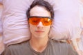 Young man sleeps while wearing red sleep glasses with blue light filtering lenses Royalty Free Stock Photo