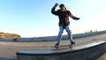 Young man slides on a skateboard along the ledge