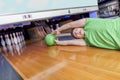 Young man sliding down a bowling alley