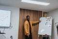 Young man in smart casual outfit pointing at a whiteboard with colorful charts and graphs during a business presentation Royalty Free Stock Photo