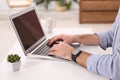 Young man with smart watch working on laptop at table in office, closeup Royalty Free Stock Photo