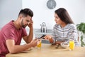 Young man with smartphone ignoring girlfriend at home