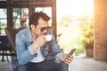 Young man with smartphone smiling relaxing at cafe.