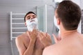 Young man smearing shaving gel on his face Royalty Free Stock Photo