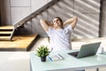 Young man smiling as he reads the screen of a laptop computer while relaxing working on a comfortable place by the wooden table at