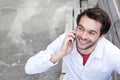 Young man smiling and calling by mobile phone outdoors Royalty Free Stock Photo