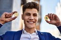 Young man smiling confident holding bitcoin and ethereum at street