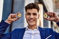 Young man smiling confident holding bitcoin and ethereum at street