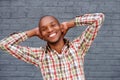 Young man smiling with hands behind head against gray wall Royalty Free Stock Photo