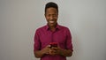 Young man smiling while holding a smartphone over an isolated white background, capturing an engaging moment of joy and technology Royalty Free Stock Photo