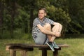 Young man smiling laughing sitting on wood table in nature fores Royalty Free Stock Photo